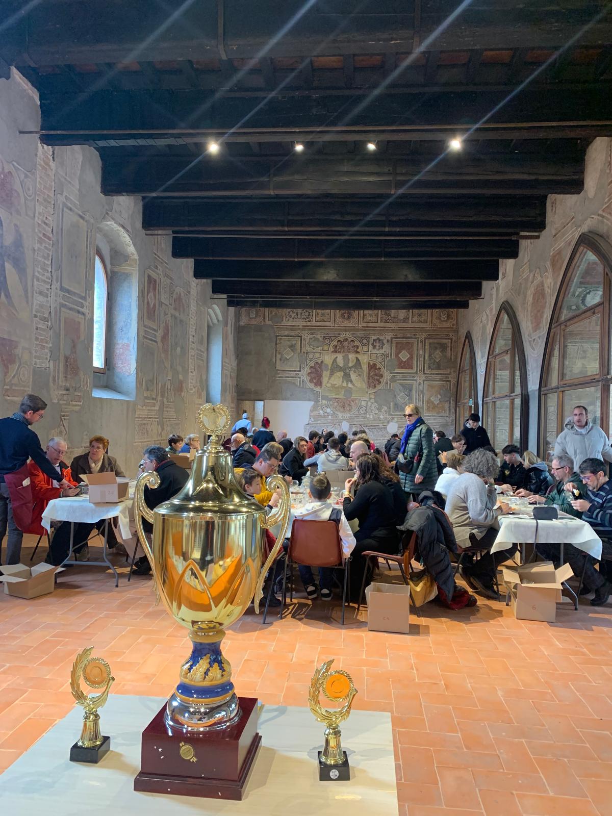 Sala affrescata del Castello Visconteo di Pandino durante gli assaggi, con il Trofeo San Lucio in primo piano